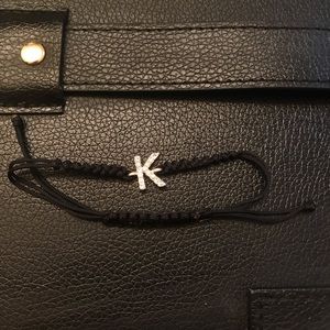 Black woven bracelet  with a K in the center.